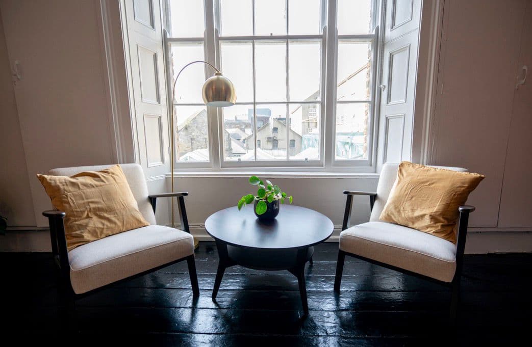 A quiet corner with two armchairs and a round table by a bright sash window